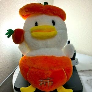 Cute stuff duck holding a mandarin in a mandarin costume
